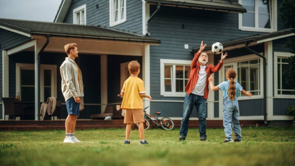 Family Spending Leisure Time Outside in the yard with Kids throwing a soccer ball.