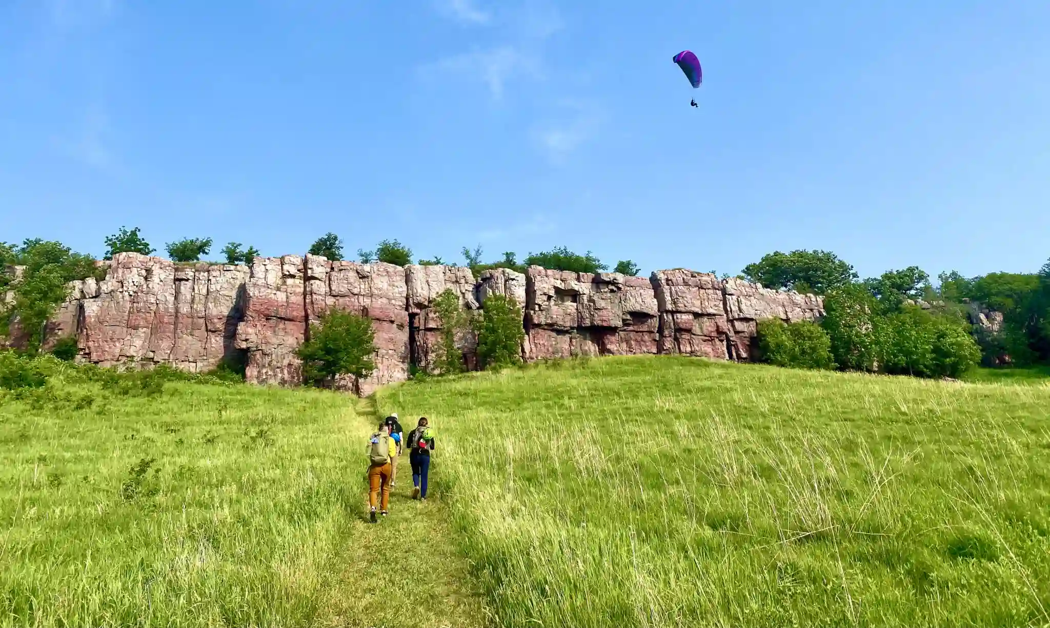 Man parasailing over hikers going to cliff