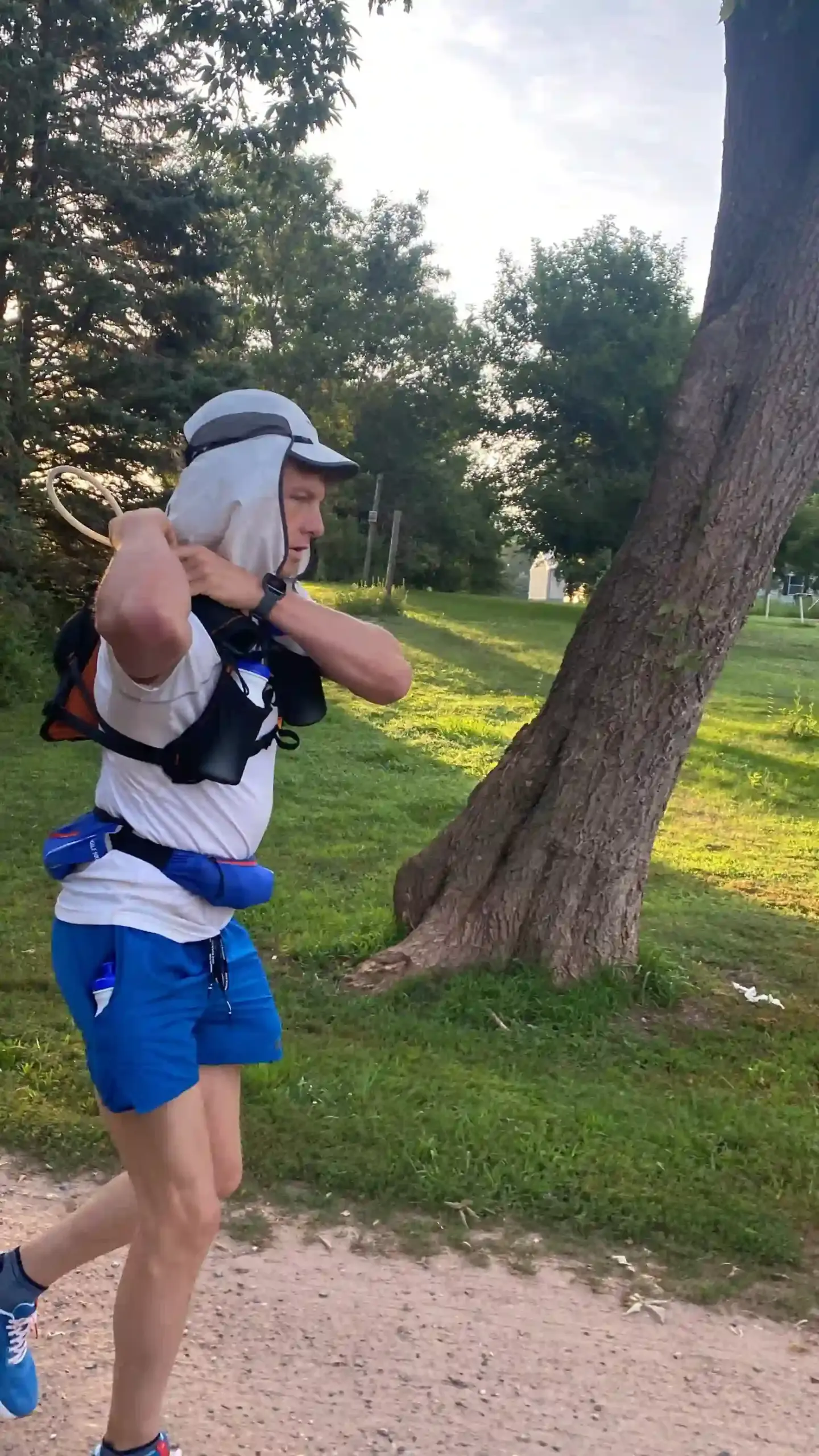 Man jogging with a water pack and a sun covering hat