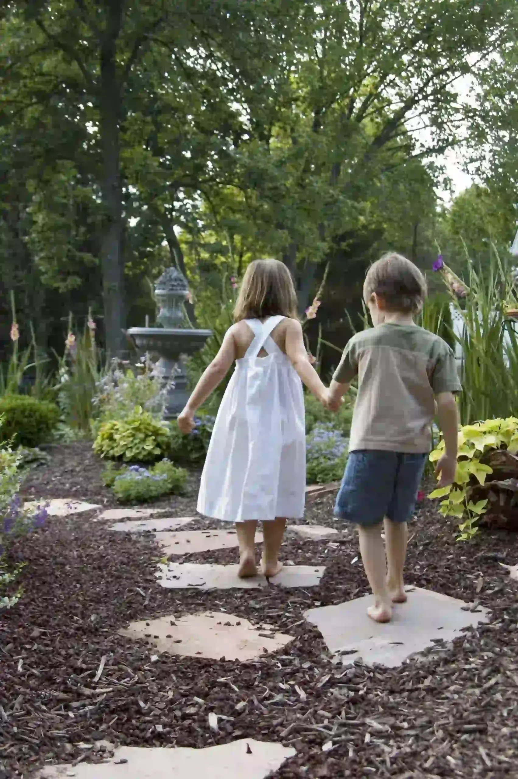 Two children holding hands walking on a path