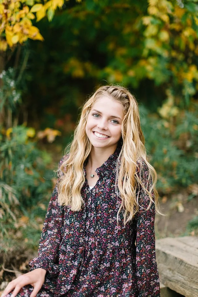 Smiling blond woman in front of trees