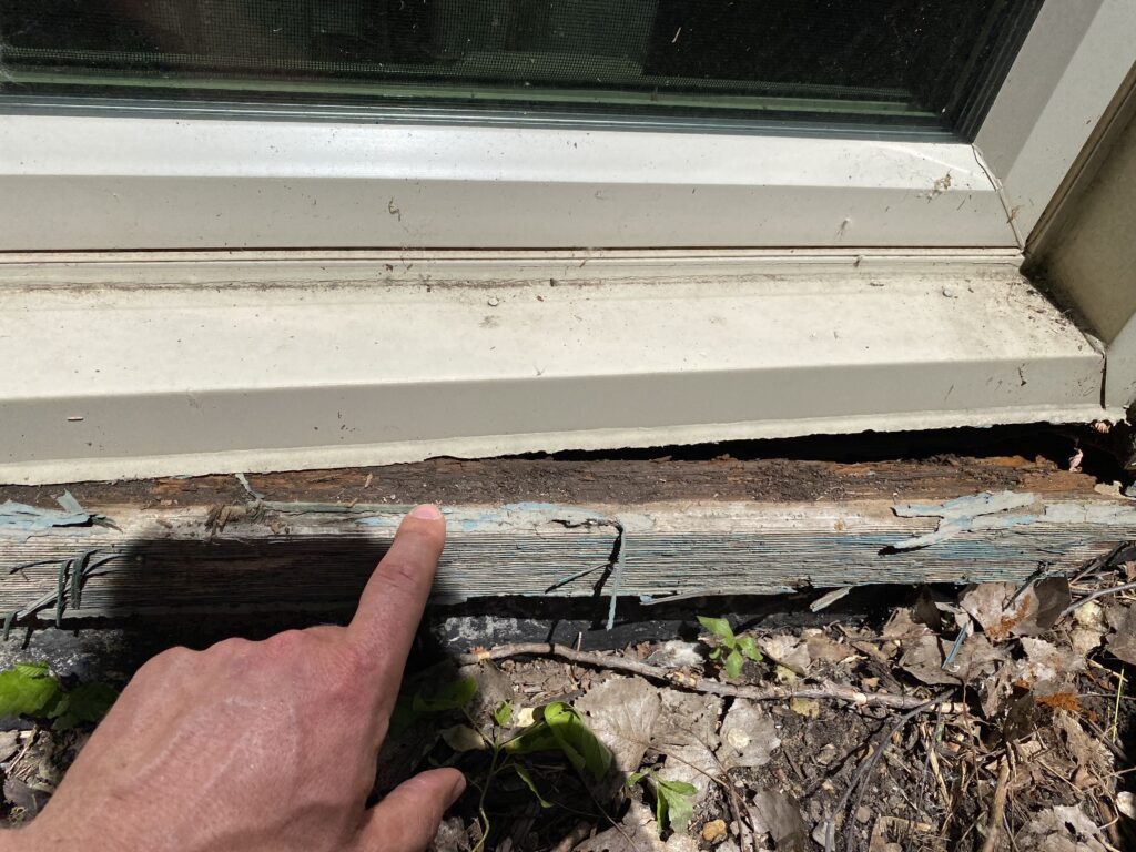 Finger resting on a board that has been pulled out from underneath the window frame 